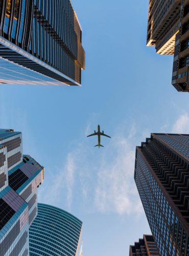 Airplane flies over Chicago's modern skyscrapers against a clear sky, highlighting urban architecture.