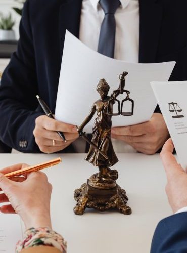 Legal professionals reviewing divorce documents in a law office with a Lady Justice statue.